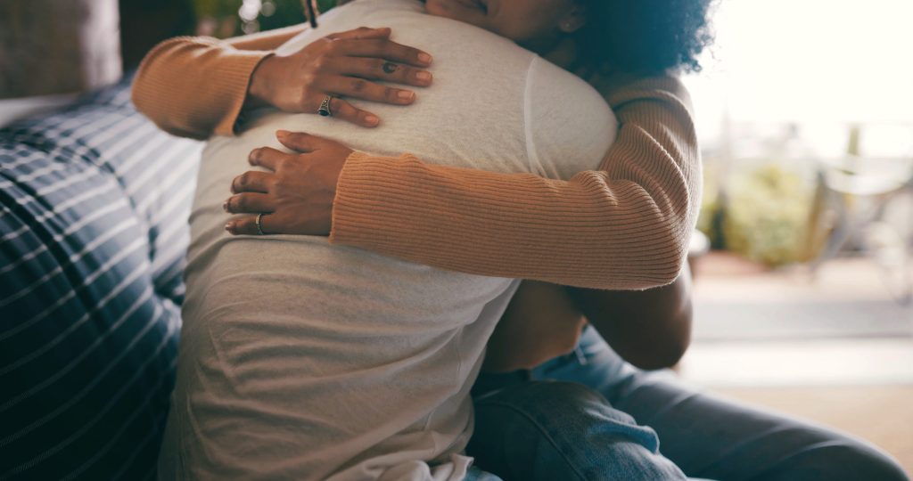 Two people hugging, sitting on a couch